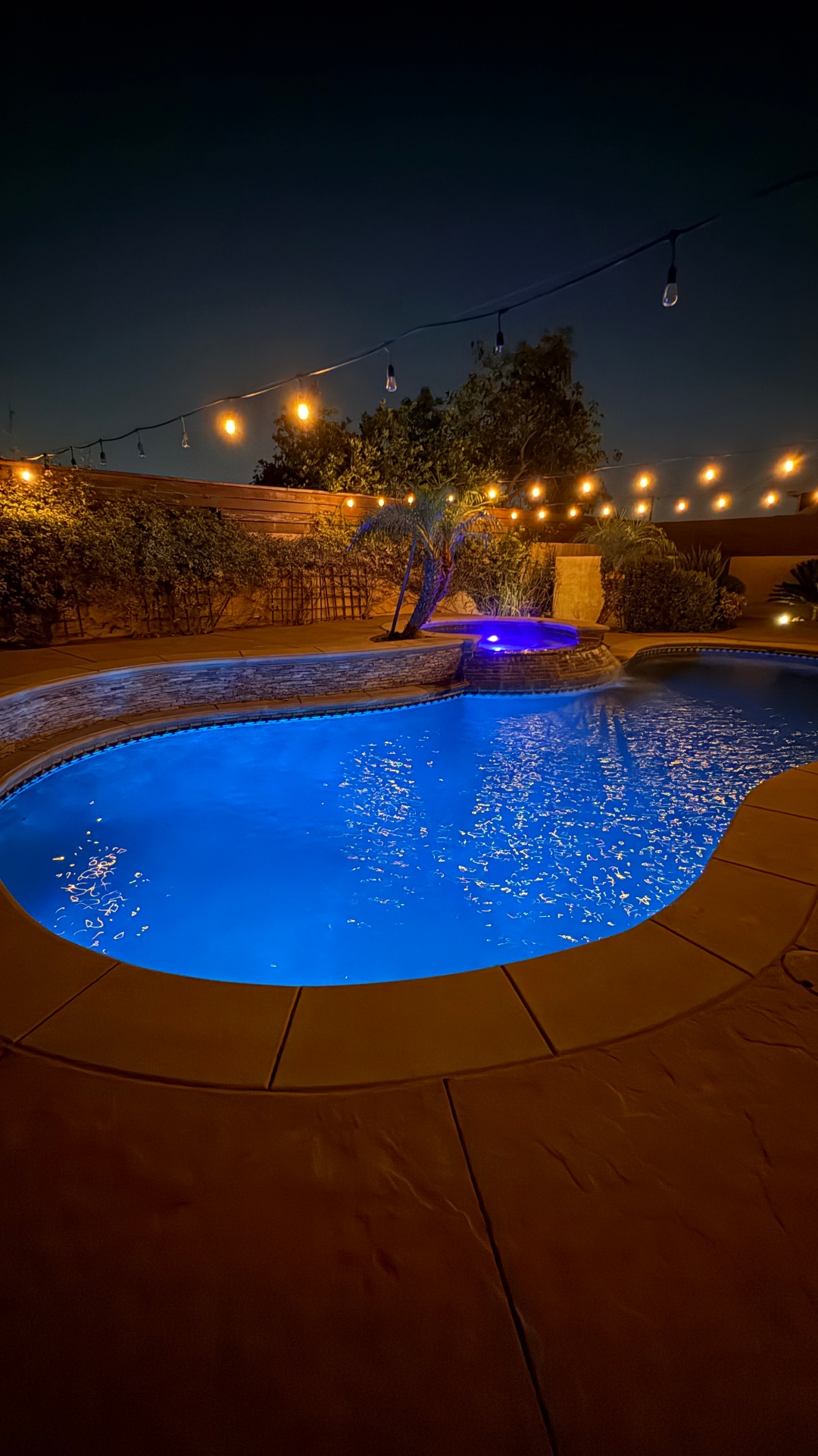 Evening pool with glowing water and string lights