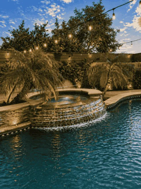 Backyard pool and spa with string lights at twilight