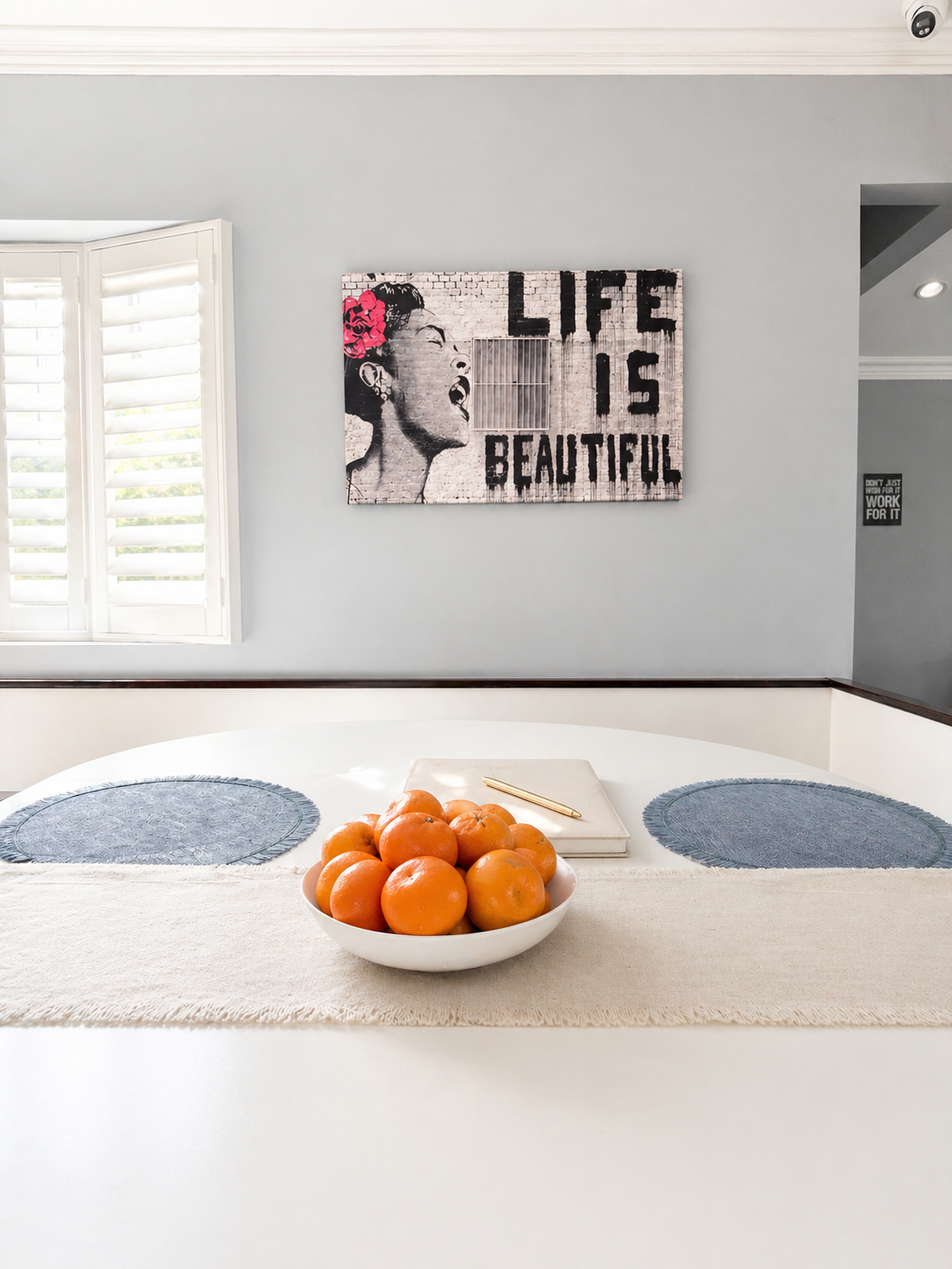 Dining table with fruit bowl and Life Is Beautiful artwork