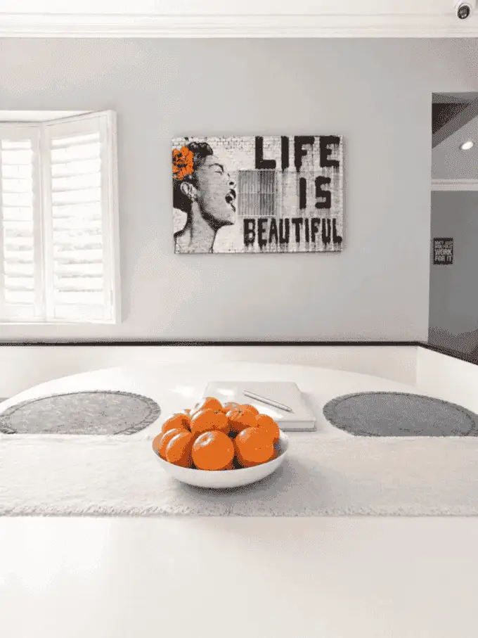 Dining table with fruit bowl and Life Is Beautiful artwork