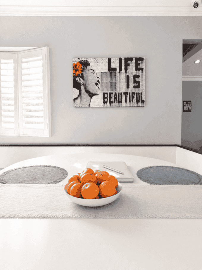 Dining table with fruit bowl and Life Is Beautiful artwork