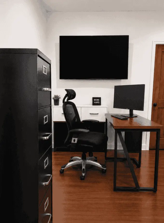 Main office with desk, ergonomic chair, and wall-mounted screen