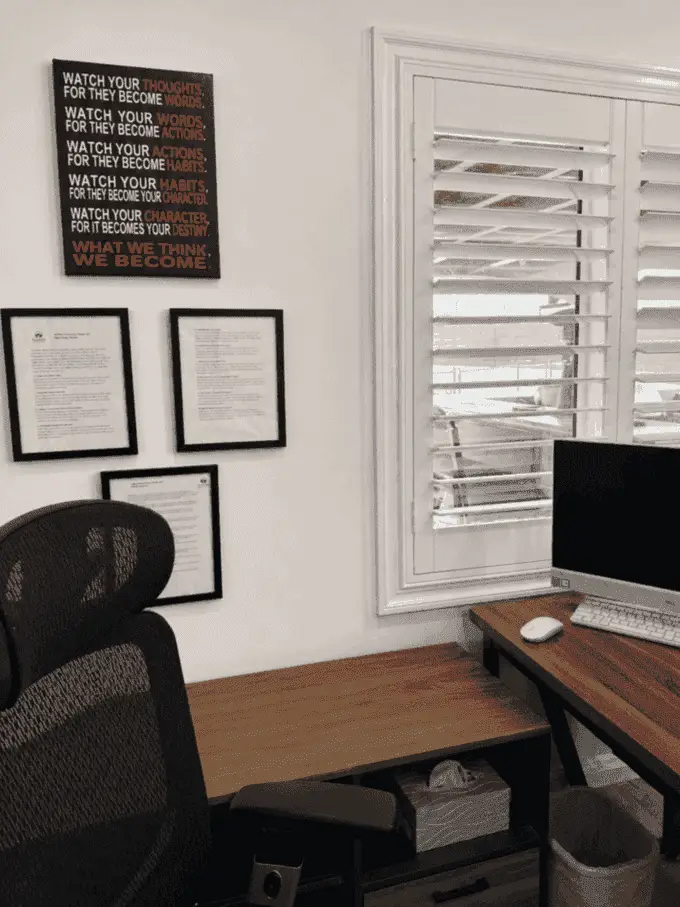 Therapy office desk with motivational wall art and shuttered window